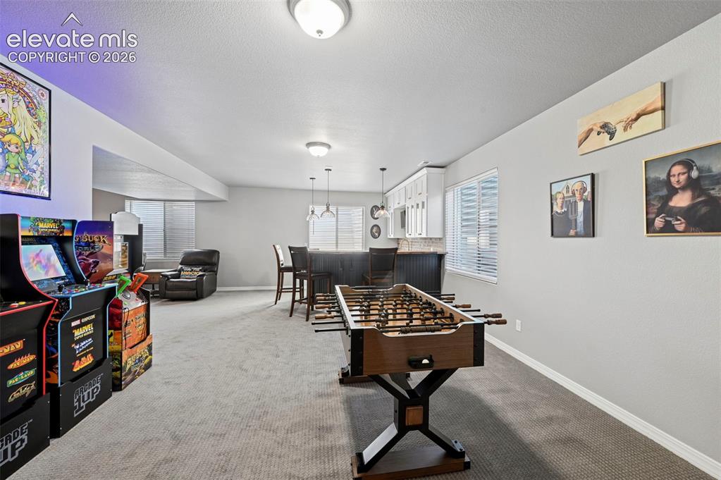 Image 34 of 50: Basement game room, with designer wetbar, arcade area, workout/gym area, an