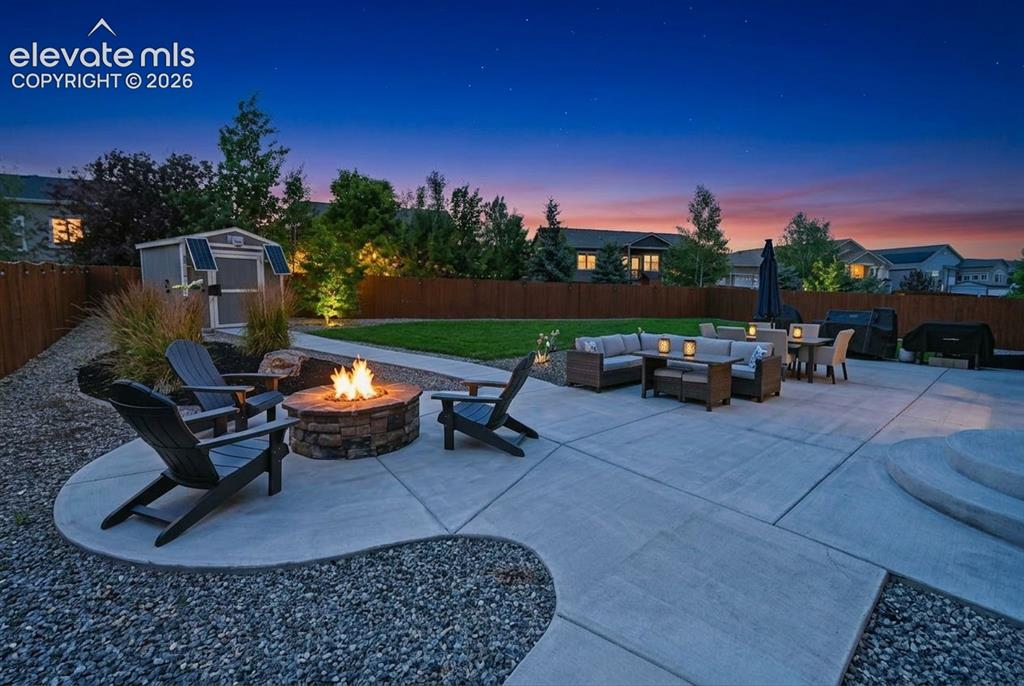 Image 45 of 50: Patio at twilight!  Designer professionally landscaped yard w/ walkway to s