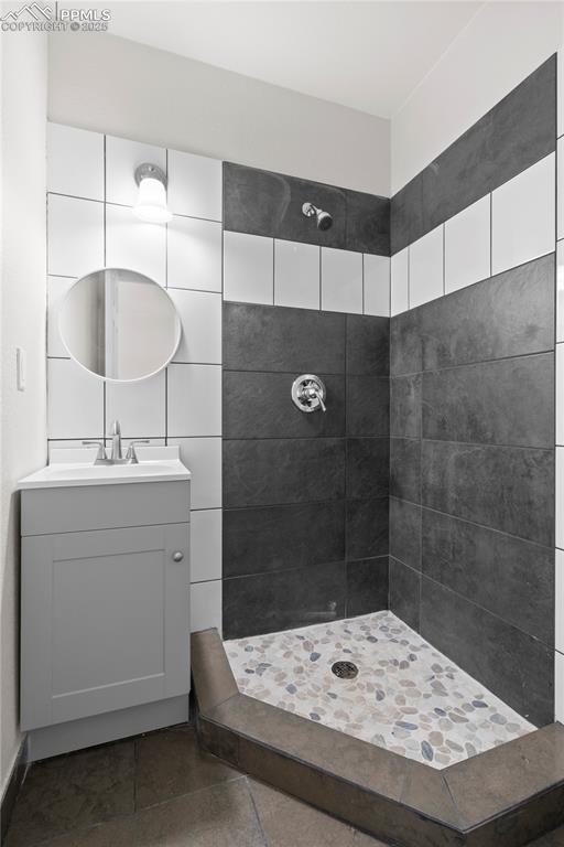 Image 12 of 35: Bathroom featuring tiled shower, vanity, and tile patterned floors