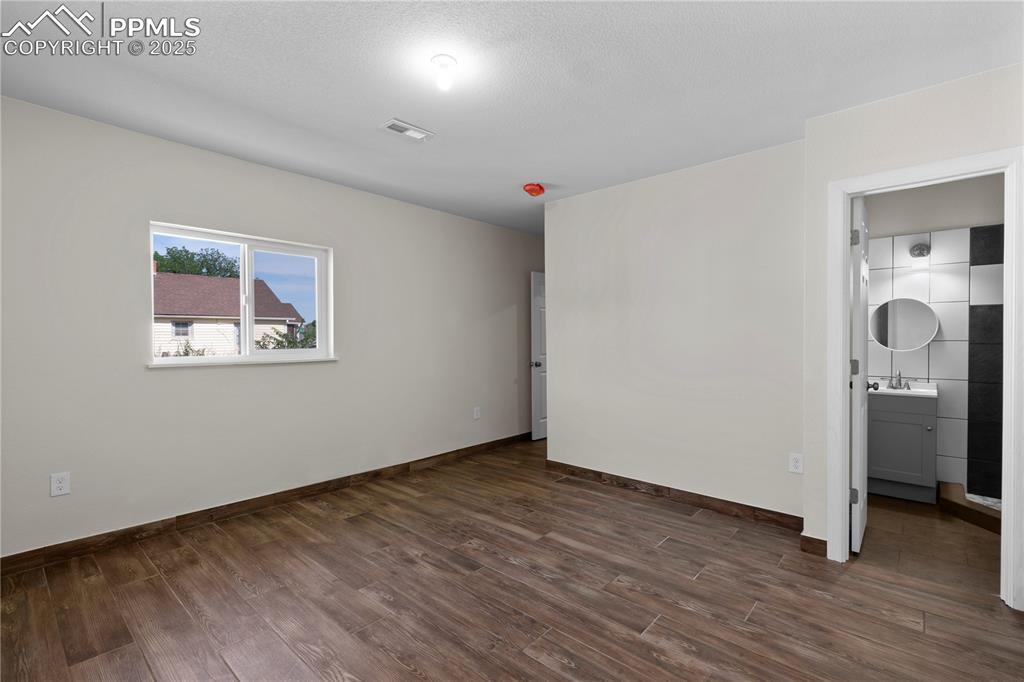 Image 13 of 35: Unfurnished bedroom featuring a sink and dark wood-style flooring