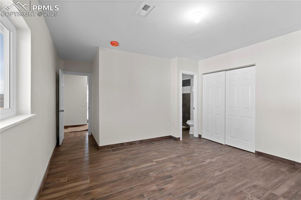 Image 14 of 35: Unfurnished bedroom with dark wood finished floors and a closet