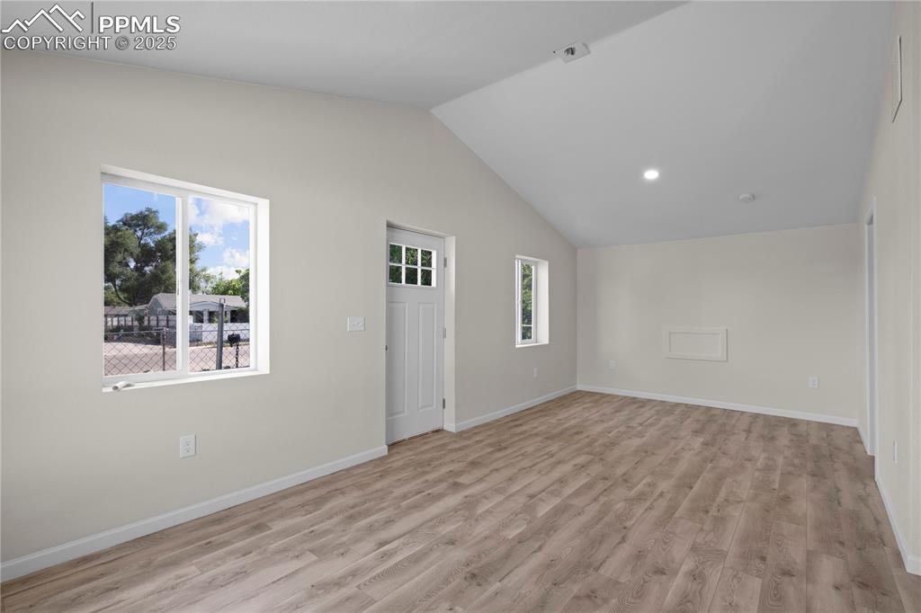 Image 19 of 35: Spare room with light wood finished floors, recessed lighting, and high vau