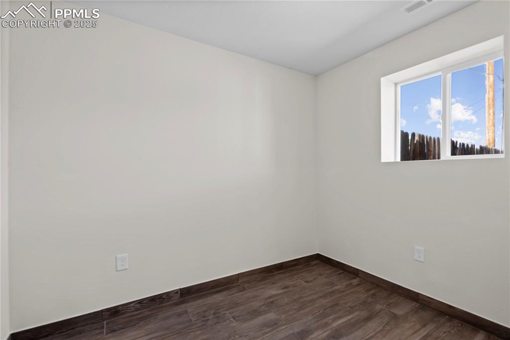 Image 21 of 35: Unfurnished room with baseboards and dark wood-style floors
