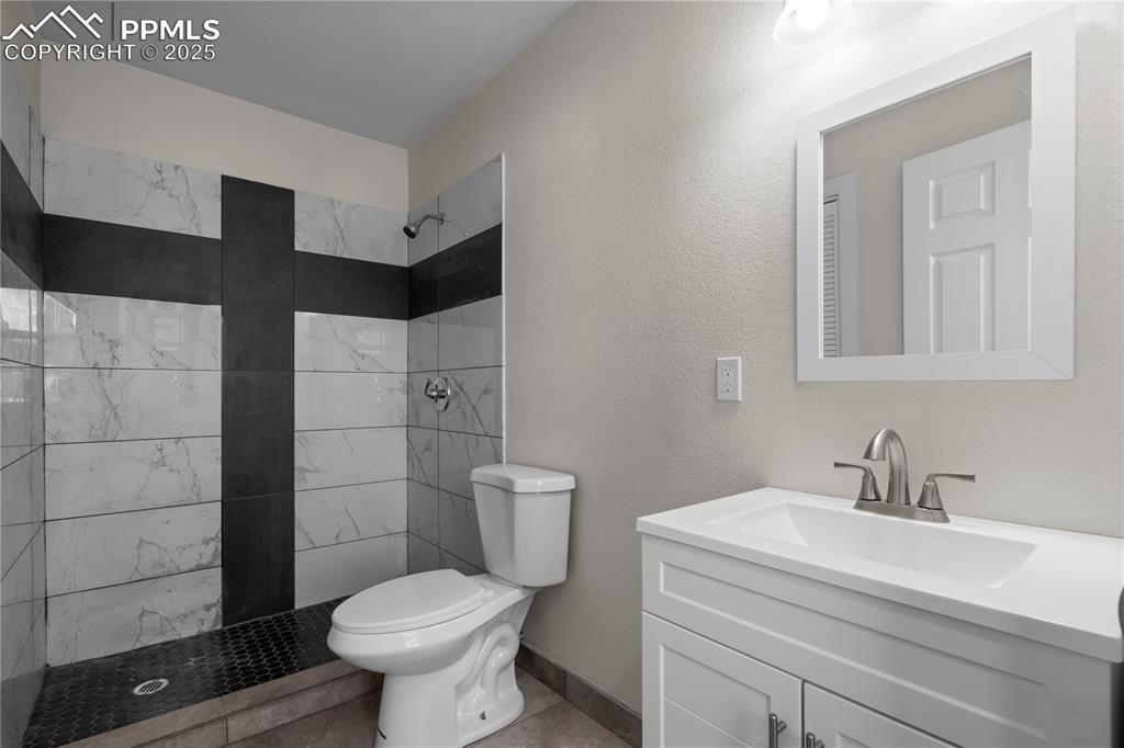 Image 25 of 35: Bathroom with tiled shower and vanity