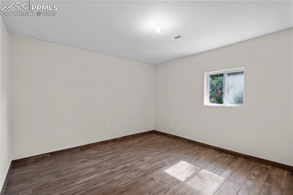 Image 26 of 35: Unfurnished room with dark wood-style floors and baseboards