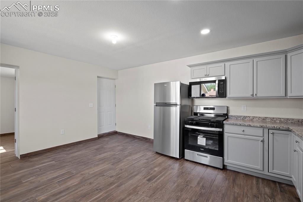 Image 28 of 35: Kitchen with appliances with stainless steel finishes, dark wood finished f