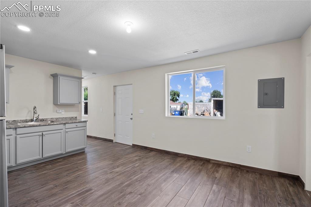 Image 30 of 35: Kitchen with electric panel, gray cabinetry, dark wood-style floors, health