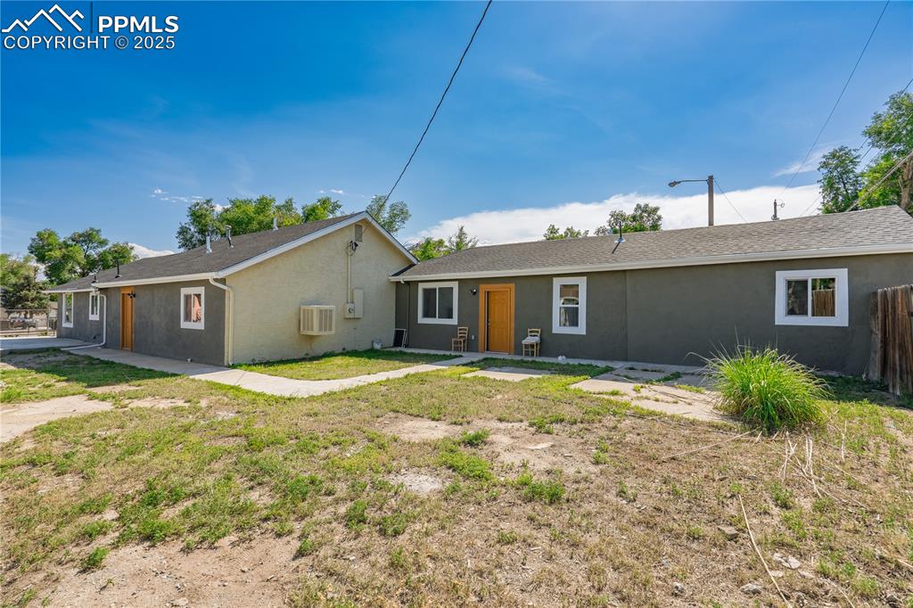 Image 34 of 35: View of front of property with stucco siding and a wall unit AC