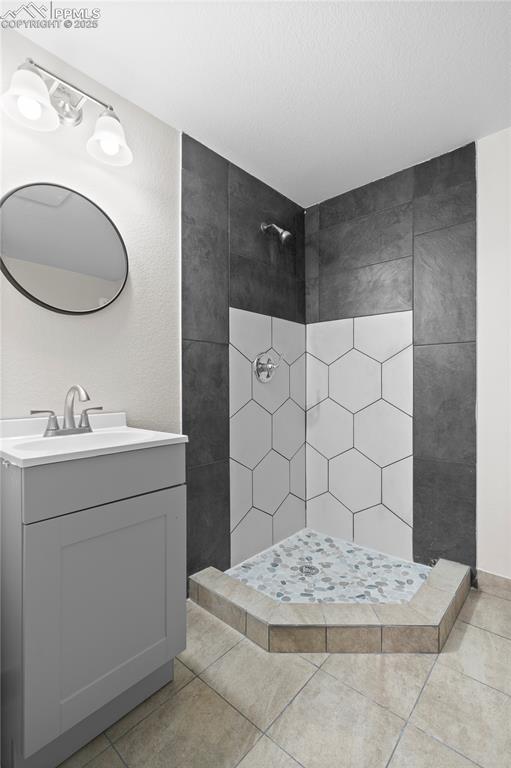 Image 8 of 35: Full bath featuring tiled shower, vanity, and tile patterned flooring