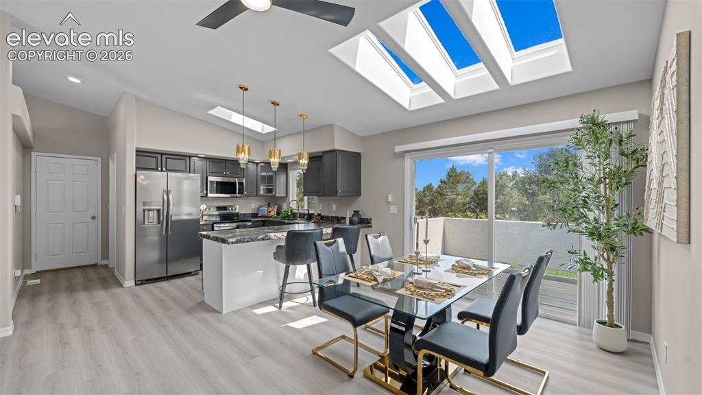 Image 12 of 48: Open-concept living area with vaulted ceilings, multiple skylights, light w