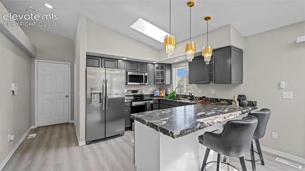 Image 15 of 48: Contemporary kitchen featuring dark wood cabinetry, stainless steel applian