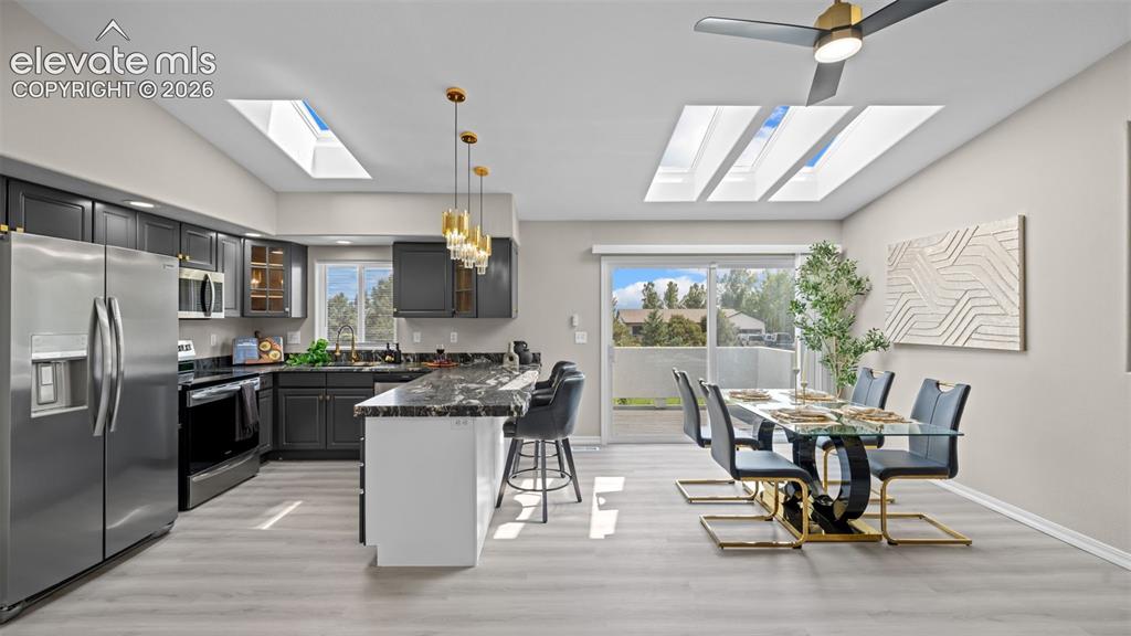 Image 16 of 48: Open-concept kitchen and dining area with vaulted ceilings and multiple sky