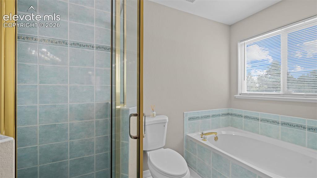 Image 26 of 48: Tiled shower stall with a clear glass enclosure and gold-toned framing, fea