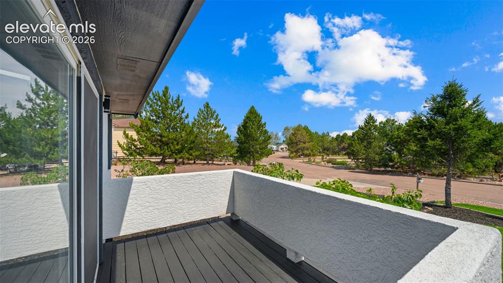 Image 5 of 48: Private balcony featuring dark composite decking, a textured stucco half-wa