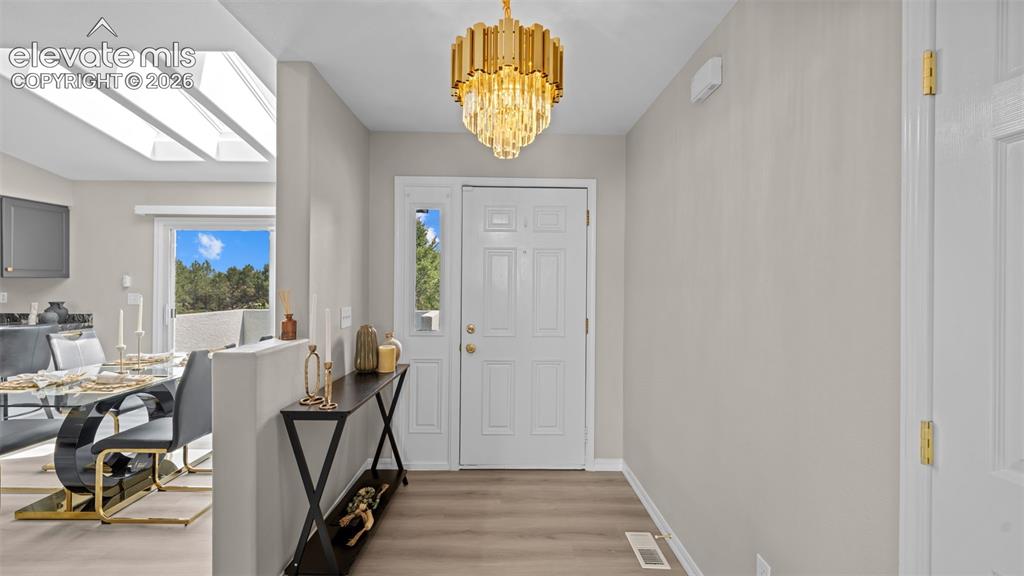 Image 6 of 48: Entrance foyer featuring a decorative chandelier, white paneled entry door
