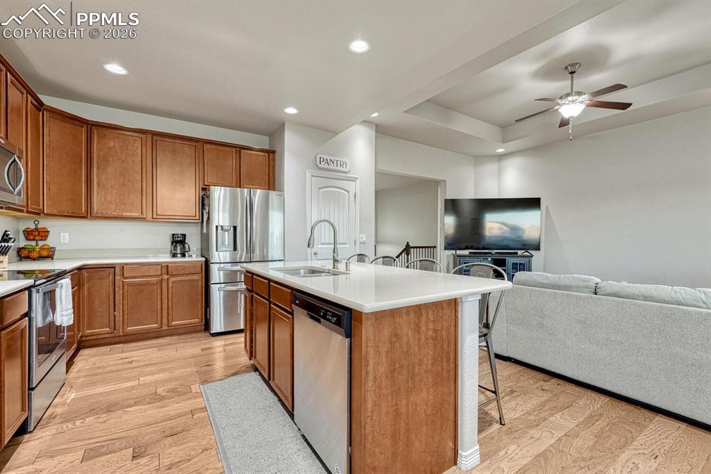 Image 10 of 46: Kitchen featuring a breakfast bar, stainless steel appliances, brown cabine