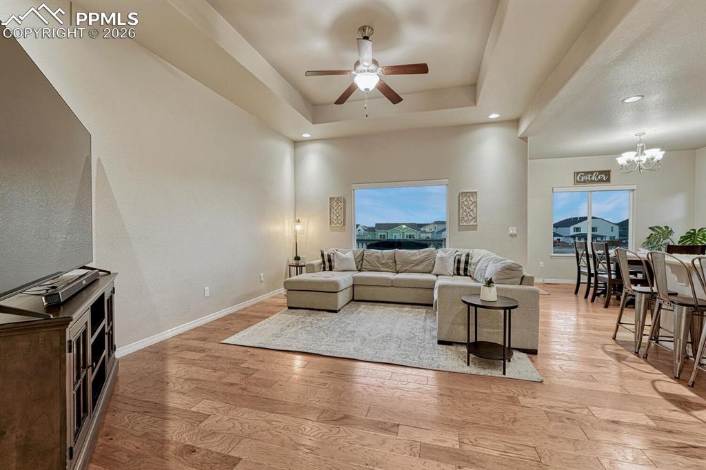 Image 14 of 46: Living room with a tray ceiling, light wood-style flooring, a chandelier, c