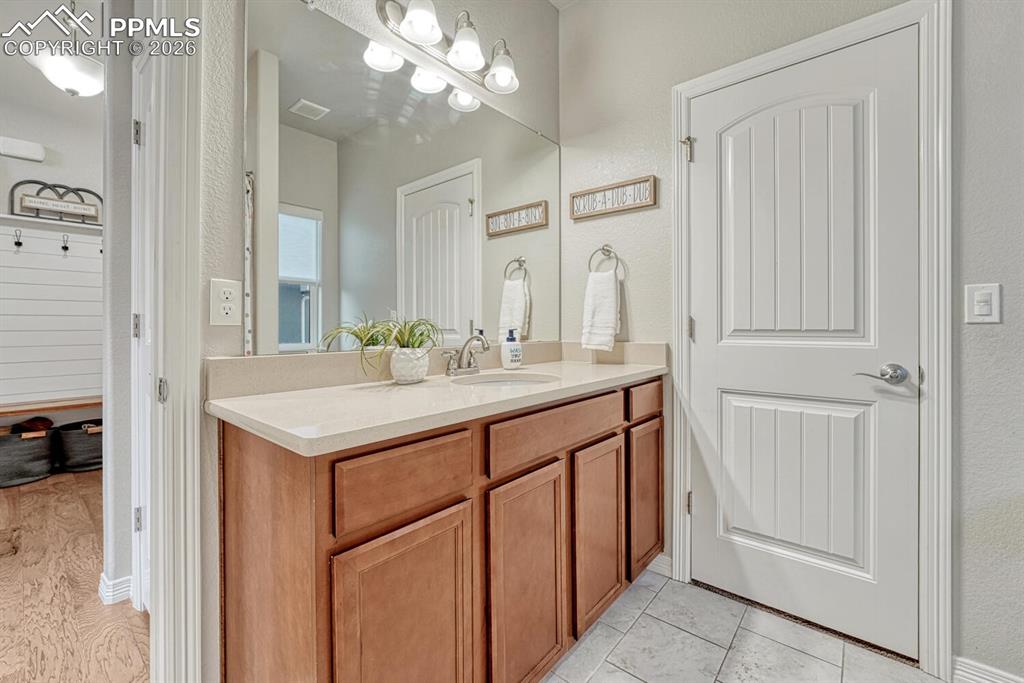 Image 20 of 46: Bathroom featuring vanity, a textured wall, and light tile patterned floors