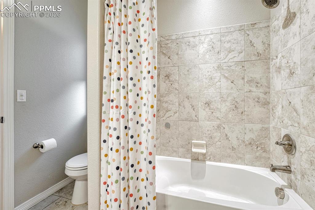 Image 21 of 46: Bathroom with a textured wall and shower / bath combination with curtain