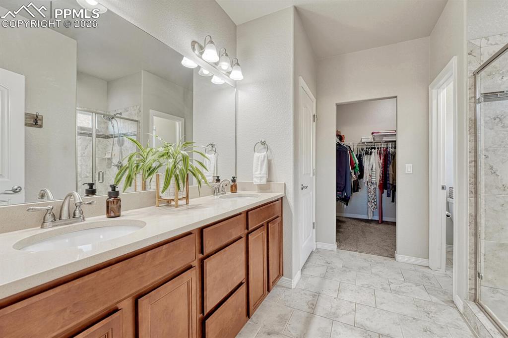 Image 25 of 46: Full bath with a shower stall, double vanity, and a walk in closet