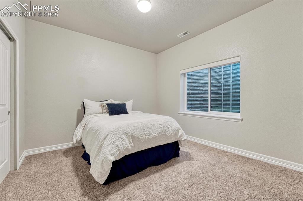 Image 32 of 46: Carpeted bedroom with a textured ceiling and a closet