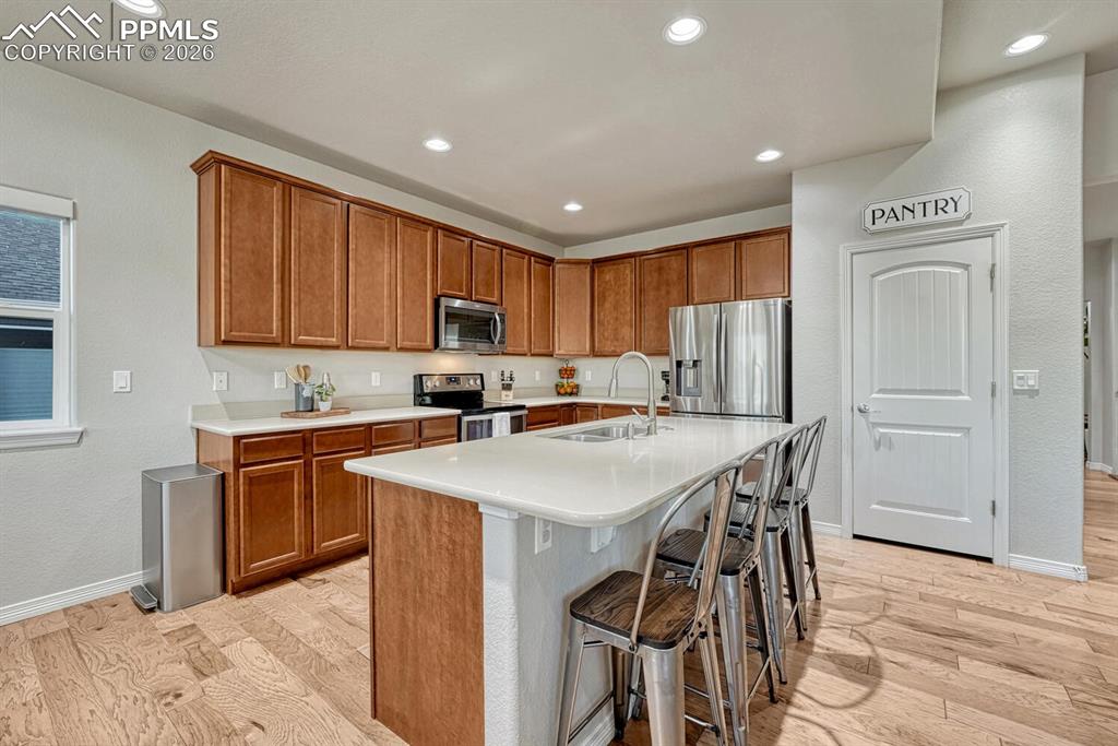 Image 9 of 46: Kitchen featuring light wood-style floors, brown cabinets, a kitchen bar, a