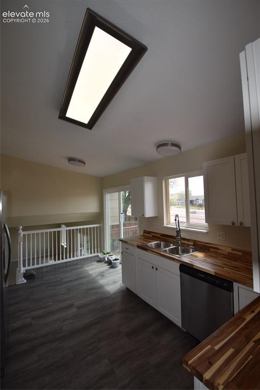 Image 10 of 45: Kitchen featuring white cabinetry, wood-finish countertops, stainless steel