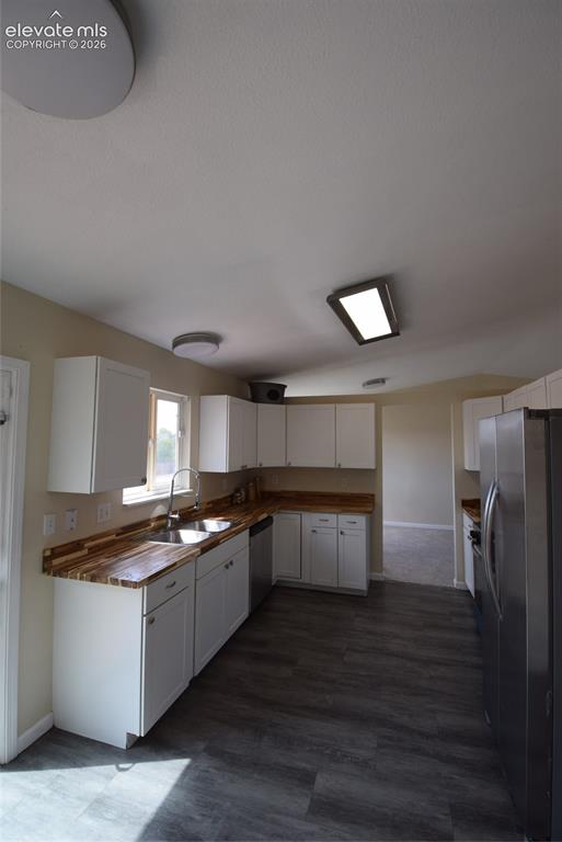 Image 11 of 45: Kitchen featuring white cabinetry, wood-finish countertops, stainless steel