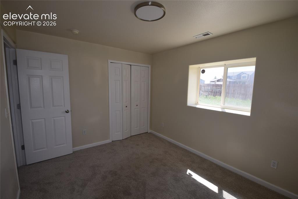 Image 19 of 45: Carpeted room featuring a white paneled door, bi-fold closet doors, a singl