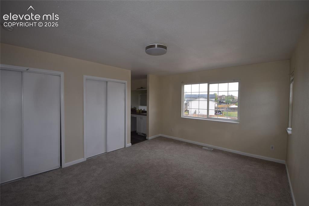 Image 28 of 45: Carpeted room with neutral-toned walls, two sets of white sliding closet do