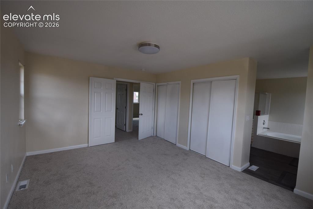 Image 29 of 45: Carpeted room with a flush-mount ceiling light fixture, two white bi-fold c