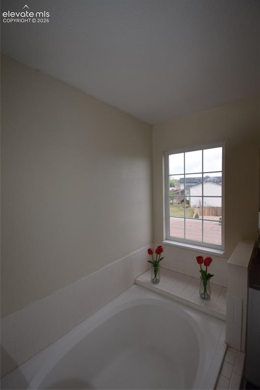 Image 31 of 45: Built-in soaking tub featuring a tiled surround, a tiled ledge, and a windo
