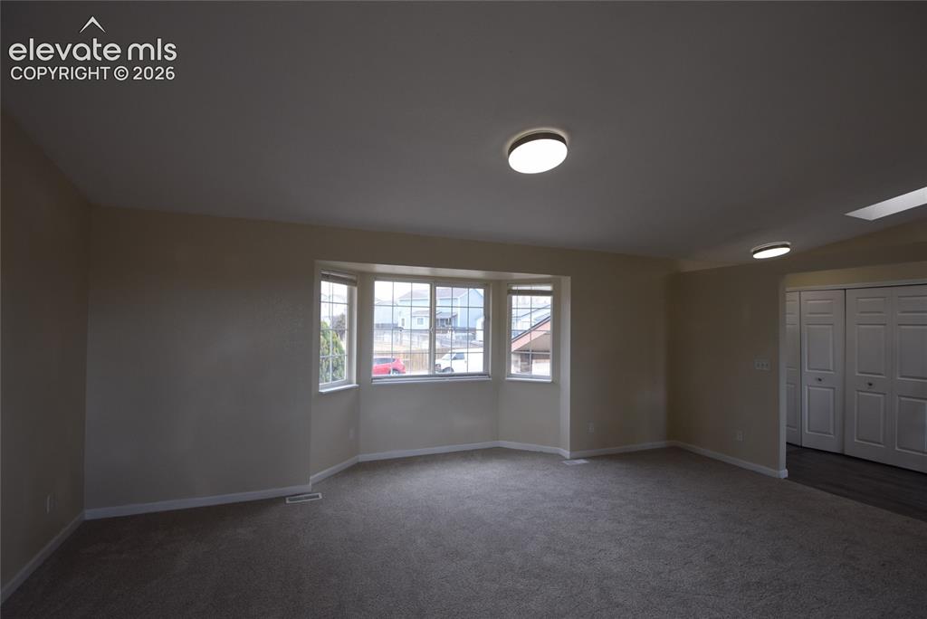 Image 32 of 45: Spacious room featuring a bay window, neutral carpeting, light neutral wall