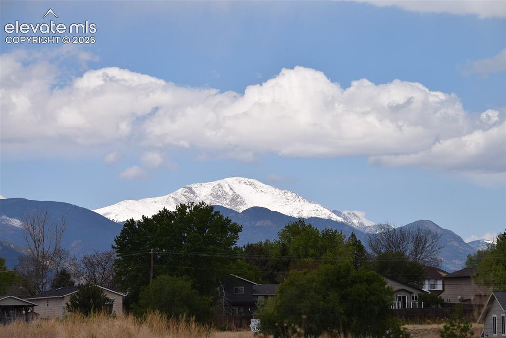 Image 38 of 45: Snow-capped mountain range under a blue sky with scattered clouds