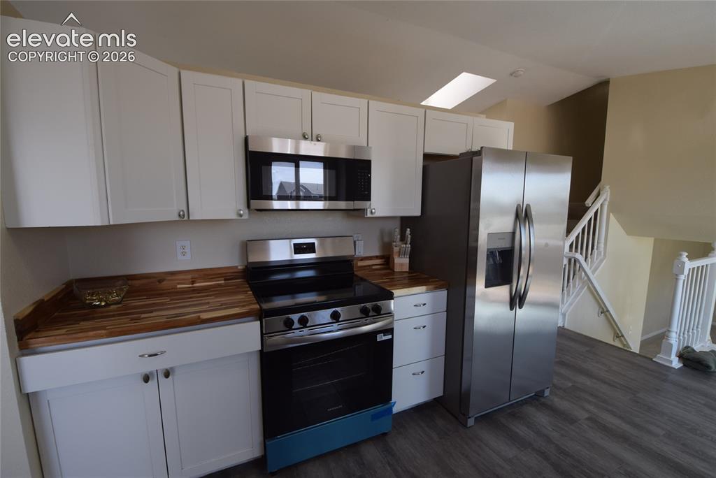 Image 8 of 45: Kitchen featuring white cabinetry, butcher block countertops, and stainless