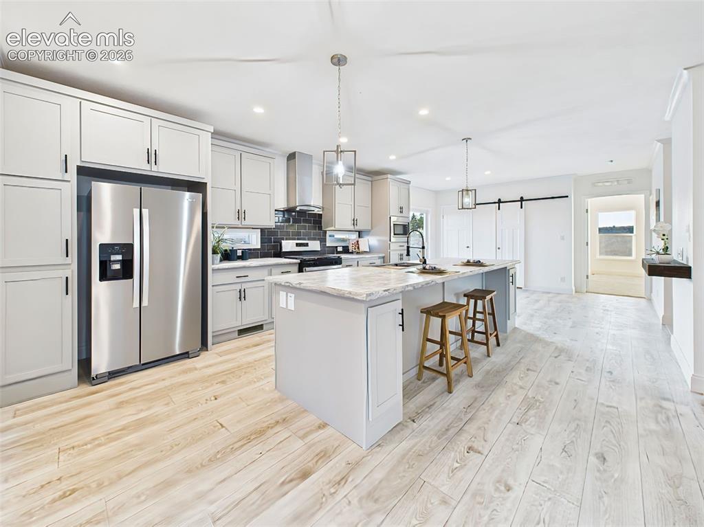 Image 10 of 50: Modern kitchen with stainless steel appliances, shaker cabinetry, sliding b