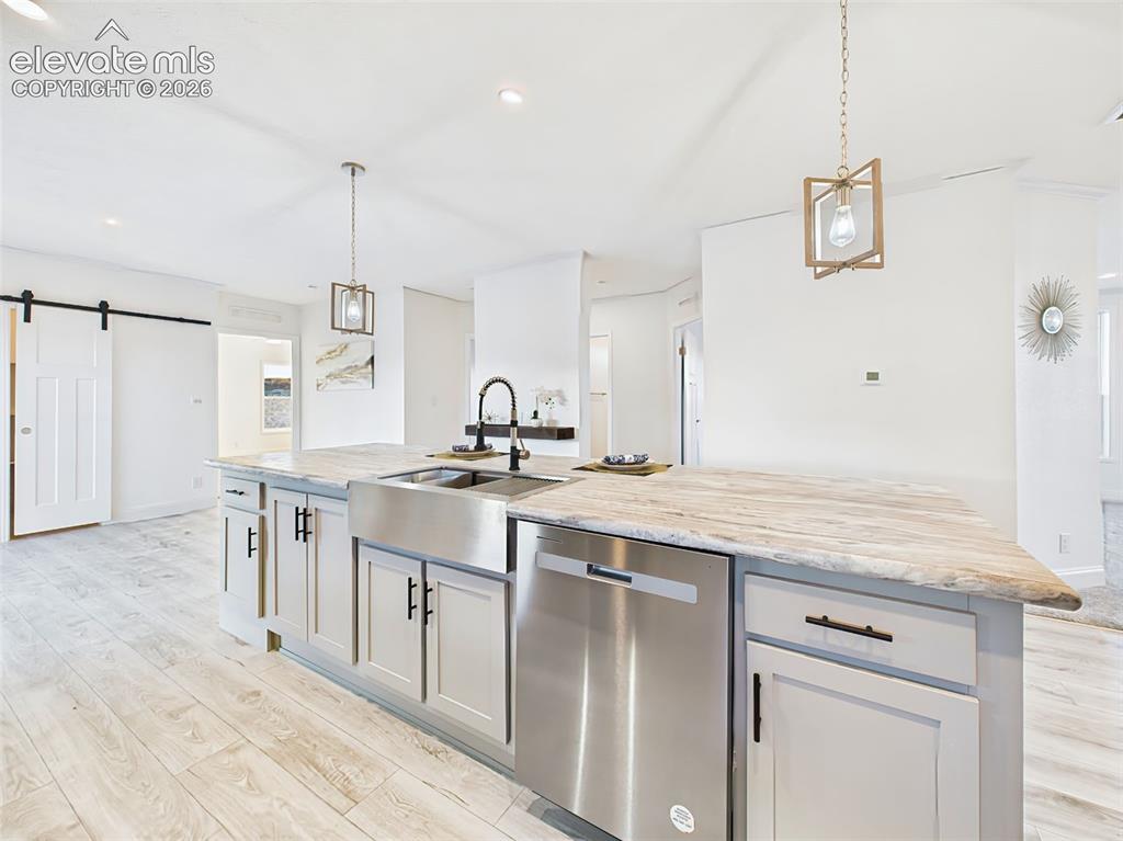 Image 16 of 50: Stainless steel dishwasher in the island and pendent lights for a clean, up