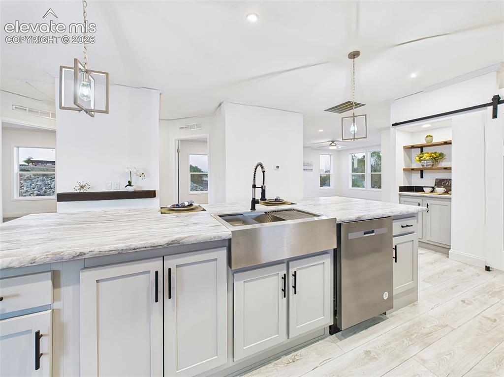 Image 17 of 50: Functional island with farmhouse sink, high-arc black faucet, and integrate