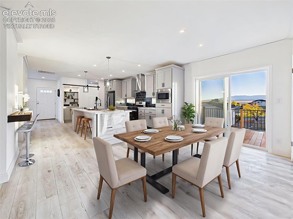 Image 22 of 50: Virtually staged dining area showing seamless flow to the kitchen and deck 