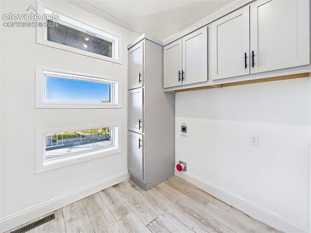 Image 39 of 50: Dedicated laundry space with custom cabinetry, and unique window detail add