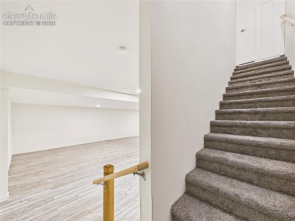Image 40 of 50: Carpeted stairs lead to the finished walk-out basement, opening to an expan