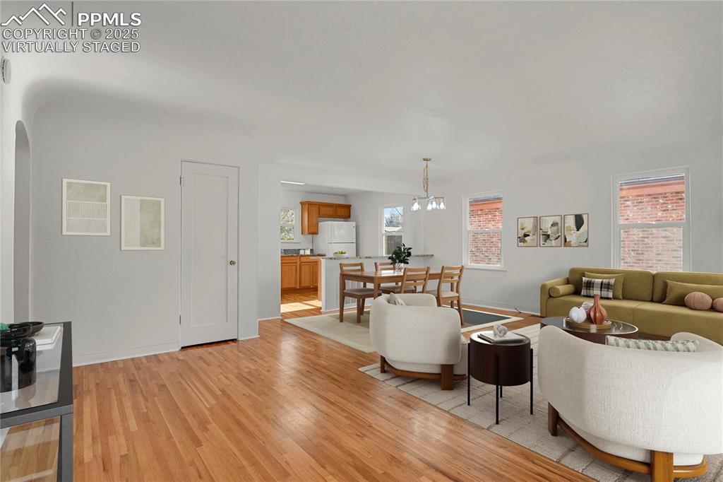Image 3 of 31: Open living, dining, and kitchen with original hardwood flooring throughout