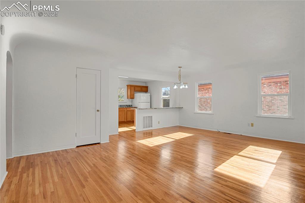 Image 4 of 31: Open living, dining, and kitchen with original hardwood flooring throughout