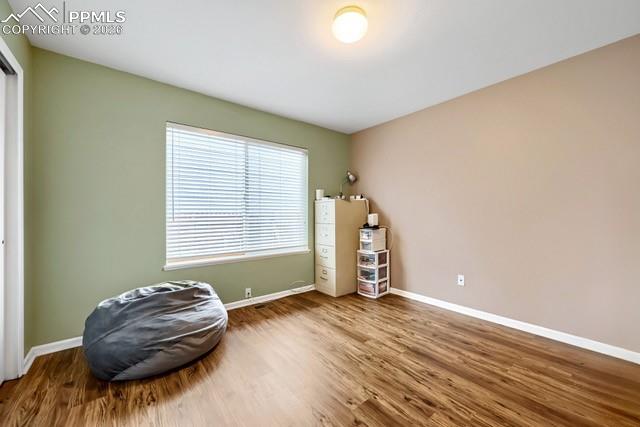 Image 14 of 32: Interior room featuring wood-finish flooring, a large window with blinds, a