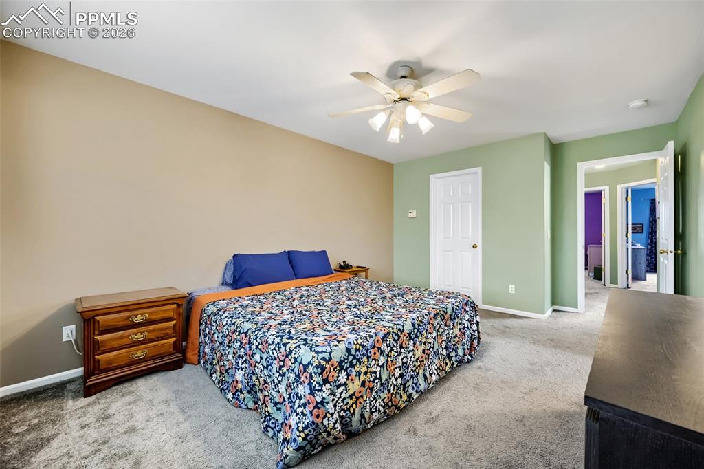 Image 19 of 32: Carpeted room with a ceiling fan, two white six-panel doors, and a doorway 