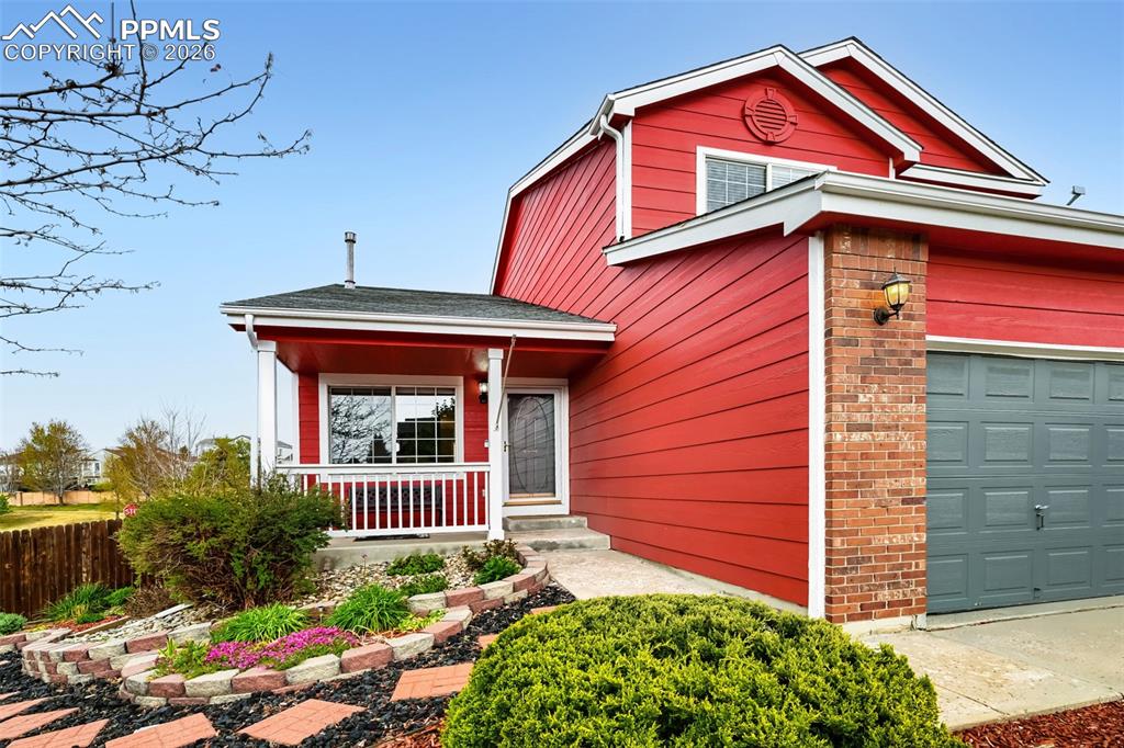 Image 2 of 32: Red siding exterior with brick accents, an attached two-car garage, and a c