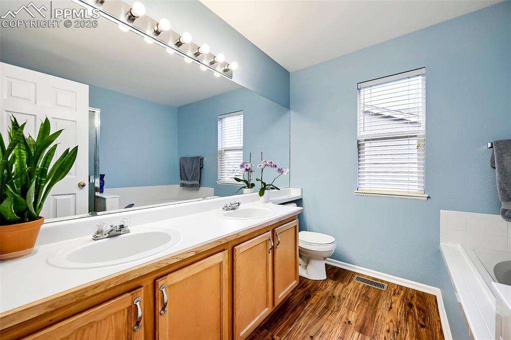 Image 21 of 32: Bathroom featuring a dual vanity with light wood cabinetry, a large mirror,