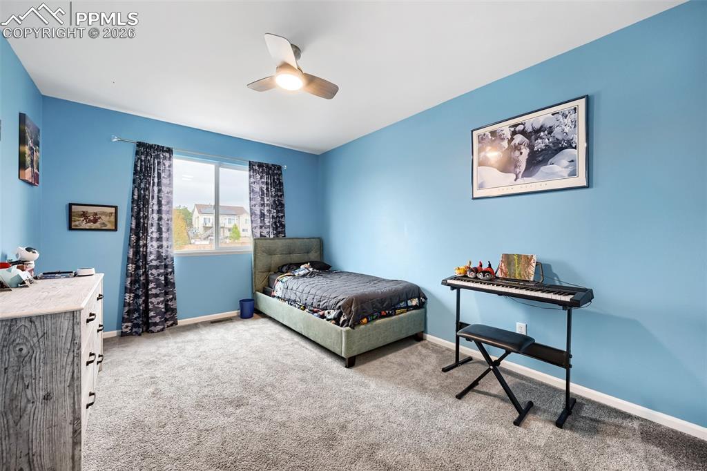Image 23 of 32: Room featuring light blue walls, grey carpeting, and a ceiling fan with int