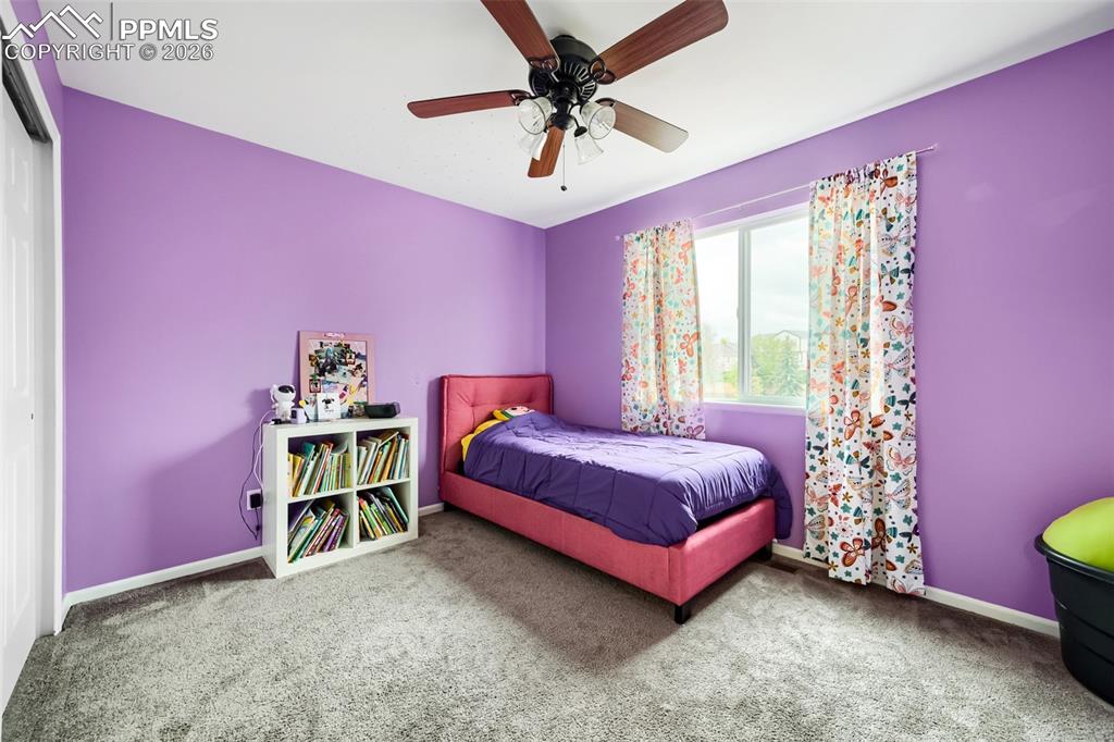 Image 24 of 32: Carpeted room featuring a ceiling fan with light fixture, a window with whi
