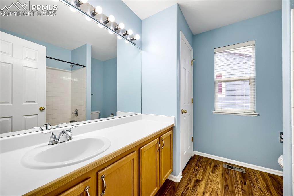 Image 27 of 32: Bathroom vanity with a white countertop and oval sink, illuminated by a mul